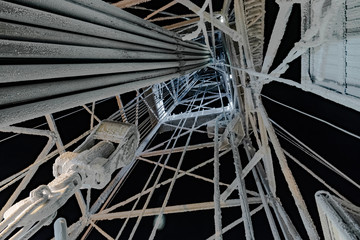 Snow-covered rig equipment at winter polar night. Inside view. Against the background of the black sky.