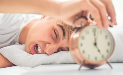 Young man is morning shocked grimace waking up alarm clock