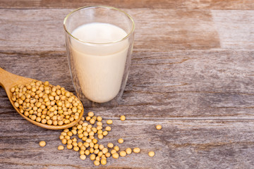 glass of fresh soymilk and soy beans on wooden table