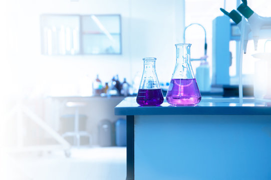 two science glass flask with purple solution on laboratory water sink for chemistry education background