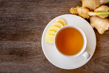  white cup of hot ginger tea  isolated on wood table background .