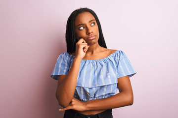 African american woman wearing striped t-shirt standing over isolated pink background with hand on...
