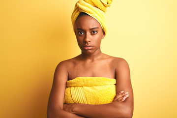 African american woman wearing towel after shower standing over isolated yellow background skeptic...