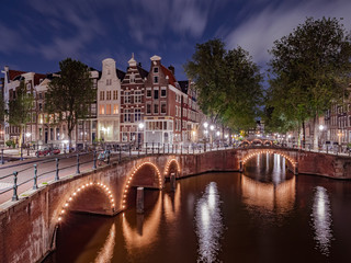 Panorama of the illuminated bridges on the channels at night. Cityscape of Amsterdam, the Netherlands at dusk