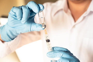 Nurse or doctor hand in blue glove holding flu, measles vaccine vial and syringe wiht needle for pregnant women vaccination, medicine and drug concept