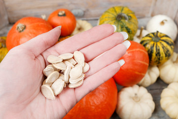 Woman is holding a pumpkin seeds in her hand.