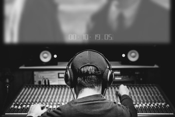 back of asian male professional producer, sound engineer, composer mixing audio track and music score on movie in sound studio. advertising, movie, drama post production concept