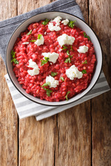 Homemade Italian Orzotto (perlotto) from barley with beets and goat cheese close-up on a plate. Vertical top view
