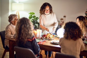 Beautiful group of women smiling happy and confident. Carving roasted turkey celebrating christmas at home