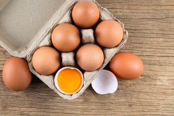 Closeup of raw chicken eggs in egg box on brown wooden background, organic food from nature good for health