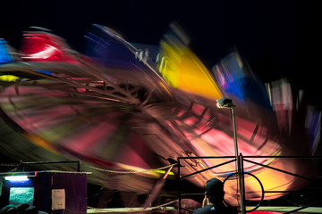 Amusement park ride fast spinning carousel roundabout with motion blur. Fun fair carnival  rides at fairground. Family vacation, leisure and recreation concept