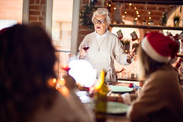 Beautiful group of women smiling happy and confident. On of them holding cup of wine speaking speech celebrating christmas at home