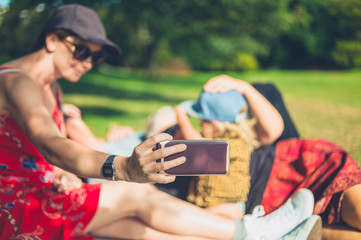 Young woman taking selfie of her family having picnic