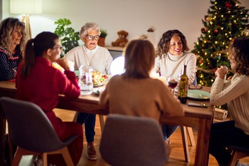 Beautiful group of women smiling happy and confident. Eating roasted turkey celebrating christmas at home
