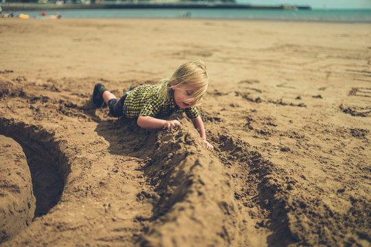 Little toddler playing with a sandcastle on the beach