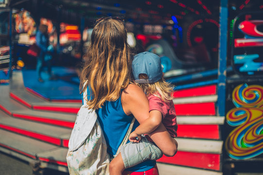 Young mother carrying her toddler at a funfair