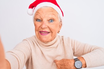 Grey-haired woman wearing Crhistmas Santa hat make selfie over isolated white background with...