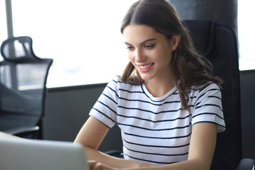 Beautiful business woman in smart casual wear working on laptop in the office