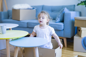 Beautiful toddler child girl playing with boxes at new home
