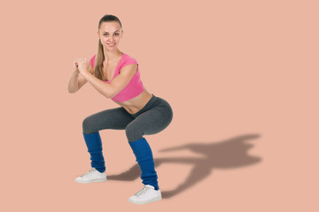 Young healthy woman in sportswear practicing squat exercise on color background