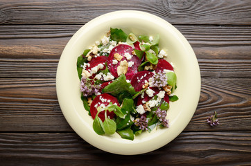 Top view at mediterranean roasted beet salad with walnuts feta cheese oregano and mash leaves on wooden table