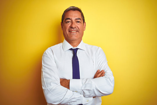 Handsome Middle Age Businessman Standing Over Isolated Yellow Background Happy Face Smiling With Crossed Arms Looking At The Camera. Positive Person.