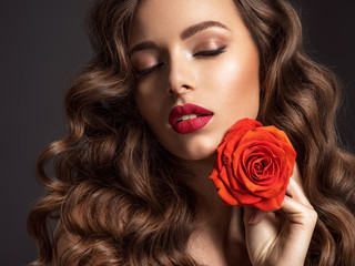 Fototapeta na wymiar Beautiful woman with brown hair. Beautiful face of an attractive model with fashion makeup. Woman with beauty long curly hair. Closeup portrait of a caucasian female. Stunning girl.
