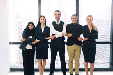 Group of diverse professional business people standing holding each other hands and smiling in the office for successful work. People working in multinational company and good cooperation concept
