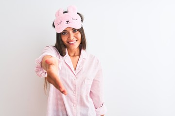 Young beautiful woman wearing sleep mask and pajama over isolated white background smiling friendly...
