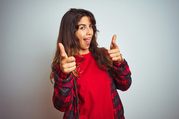 Young beautiful woman wearing red t-shirt and jacket standing over white isolated background pointing fingers to camera with happy and funny face. Good energy and vibes.