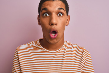 Young handsome arab man wearing striped t-shirt standing over isolated pink background scared in shock with a surprise face, afraid and excited with fear expression
