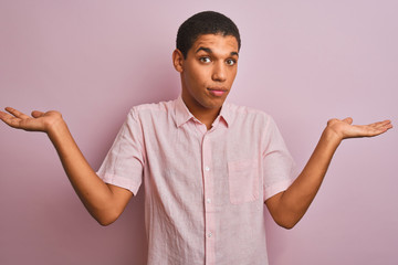 Young handsome arab man wearing casual shirt standing over isolated pink background clueless and...