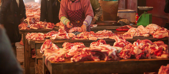 Vietnamese female butcher cutting pork meat.