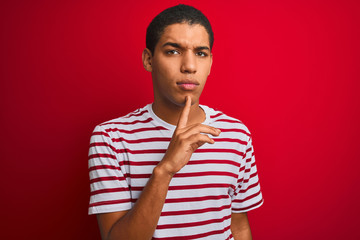 Young handsome arab man wearing striped t-shirt over isolated red background Thinking concentrated...