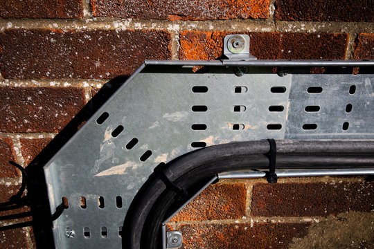 Mild steel heavy duty pre galvanised cable tray mounted on external brick wall to support electrical wiring 