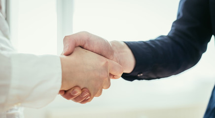 Shaking hands, concept for teamwork: Close up of man and woman shaking hands in the office