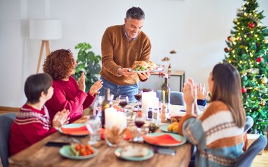 Beautiful family smiling happy and confident. One of them standing showing roasted turkey celebrating christmas at home