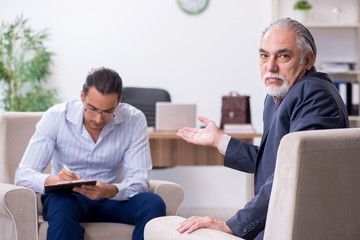 Old man visiting young male doctor psychologist