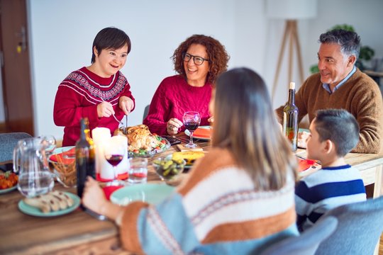 Beautiful family smiling happy and confident. One of them curving roasted turkey celebrating christmas at home