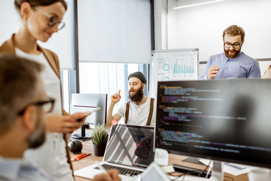 Group of diverse colleagues working on the computers in the modern office or coworking space, bearded hipster having an idea