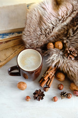 cup of coffee and fur plaid, nuts, cinnamon, books. fall or winter season background. home hygge comfort concept. copy space