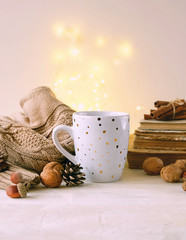 cup of tea or coffee, sweater, nuts, books. fall or winter season concept. tea time. home hygge comfort concept. soft selective focus. copy space