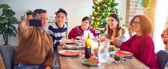 Fototapeta na wymiar Beautiful family smiling happy and confident. Eating roasted turkey make selfie by smartphone celebrating christmas at home