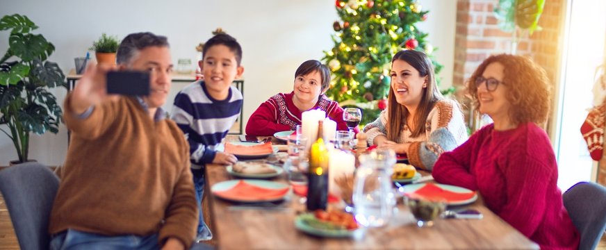 Beautiful family smiling happy and confident. Eating roasted turkey make selfie by smartphone celebrating christmas at home