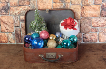 Christmas balls and suitcase on a brick wall background