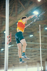 Pole vaulting - man in yellow t shirt is falling after jump with pole