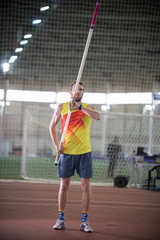 Pole vaulting - man in yellow shirt is standing with a pole in hands