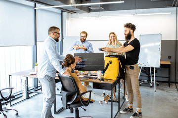 Courier delivering fresh lunches with yellow thermal bag for office workers. Concept of food delivery to employees in the office