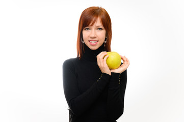 Healthy food concept. Portrait of a pretty red-haired student girl with long smooth hair on a white background in a black sweater with an apple in her hands. Talking, showing emotions, smiling.