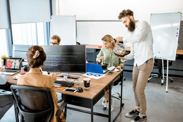 Office workers eating salad while sitting on the working place during a lunch time without leaving the office. Concept of healthy takeaway food on the work